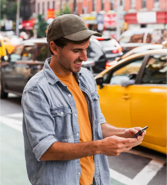 Man smiling while looking at his phone in a city street
