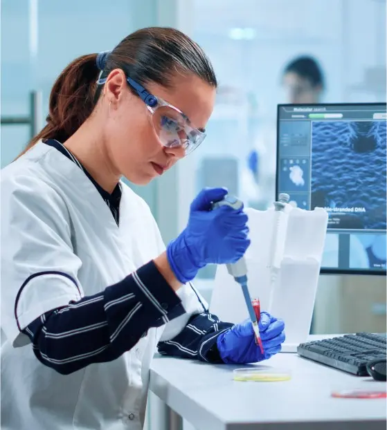 Scientist using a pipette in a lab with a computer