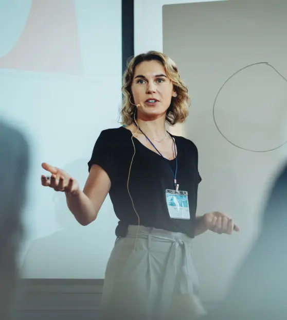 Woman presenting in front of a whiteboard with a microphone