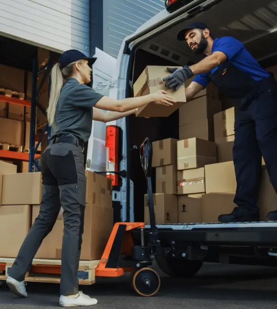 Worker hands box to delivery driver from van