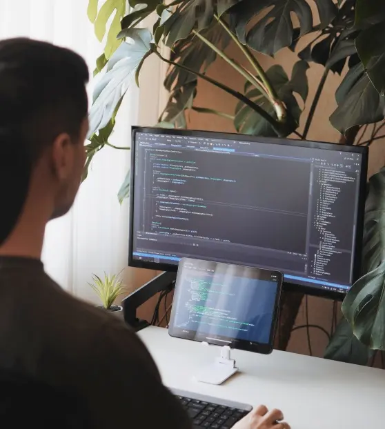 Man coding on dual screens at a desk for Mvp Development Services