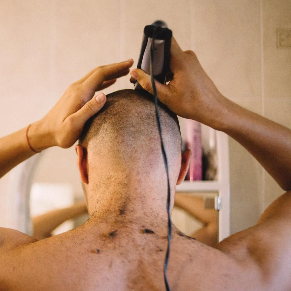 Man grooming beard using electric trimmer in front of mirror