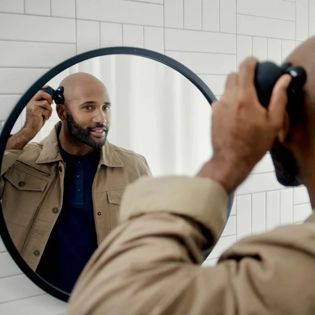Man grooming beard using electric trimmer in front of mirror